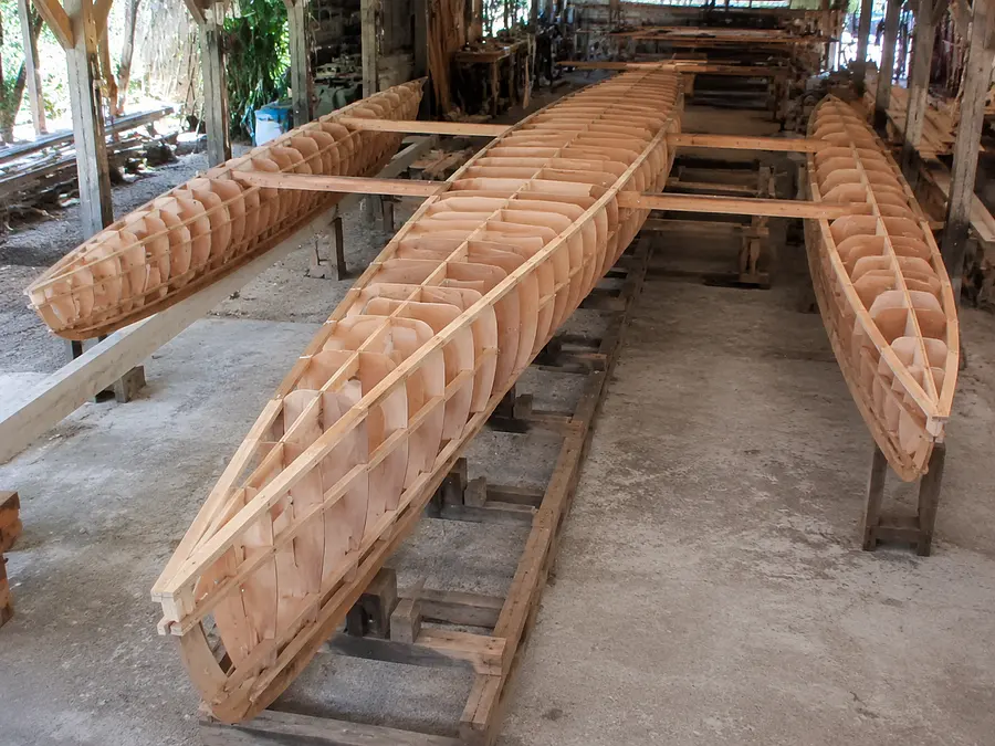 gpt-image-2 render: Photorealistic image of a wooden trimaran boat under construction in a workshop. The central hull...