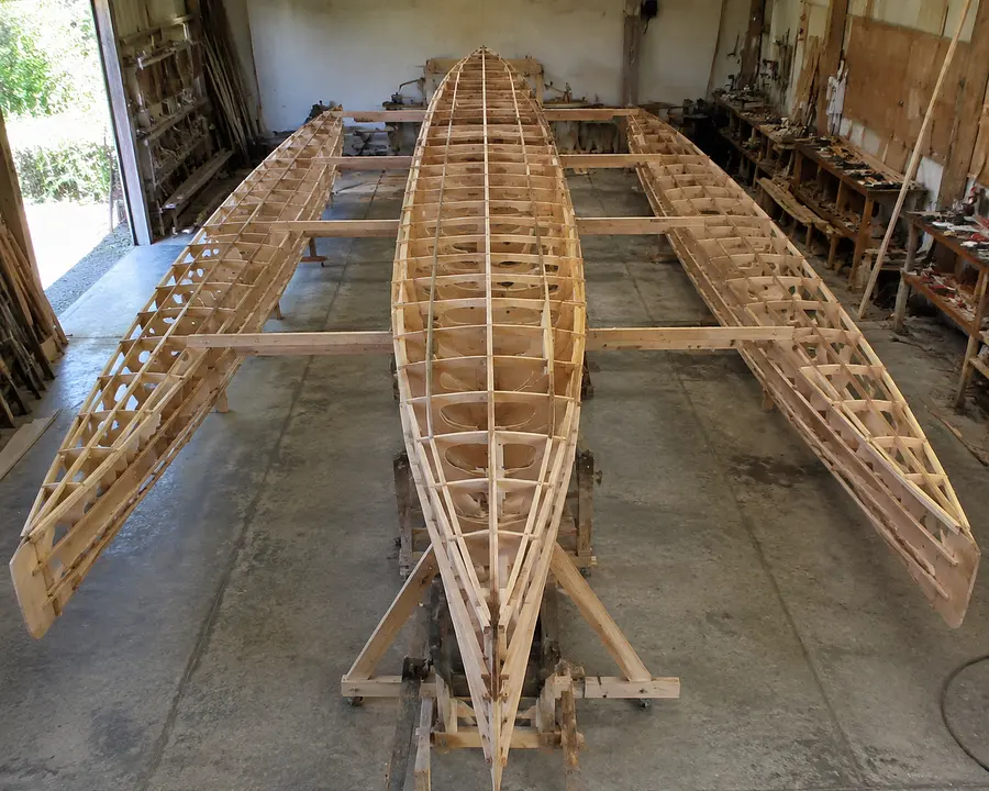 Photorealistic image of a wooden trimaran boat under construction in a worksh...
